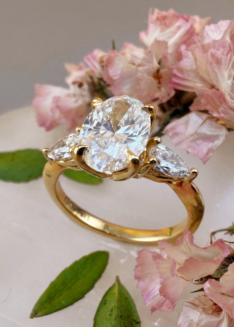 oval 1.5 carat lab grown diamond 14k gold ring perched in 2 pear cut 0.18 carat diamond .